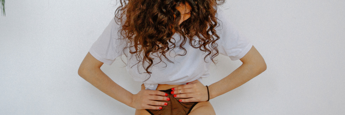 Frau hält sich den Bauch, hat Regelschmerzen